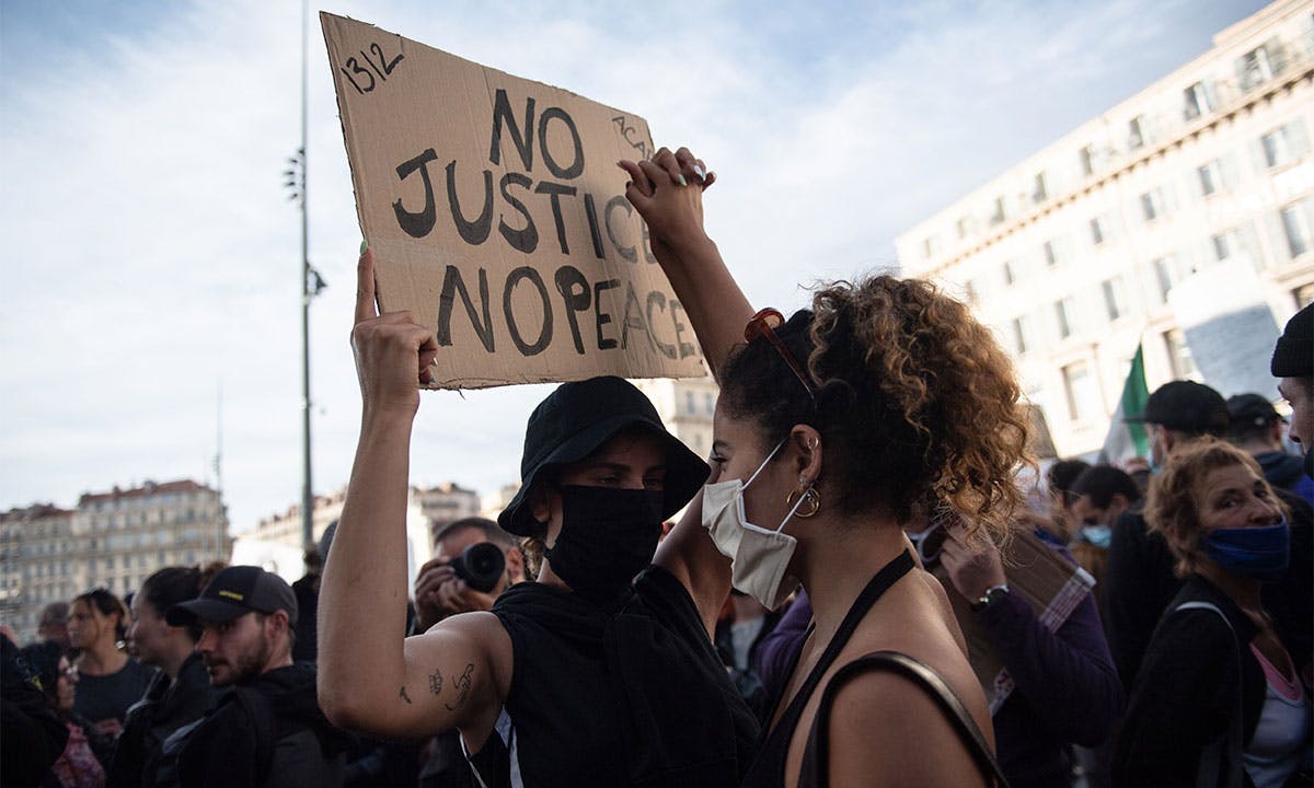 protesters hold up "no justice no peace" sign