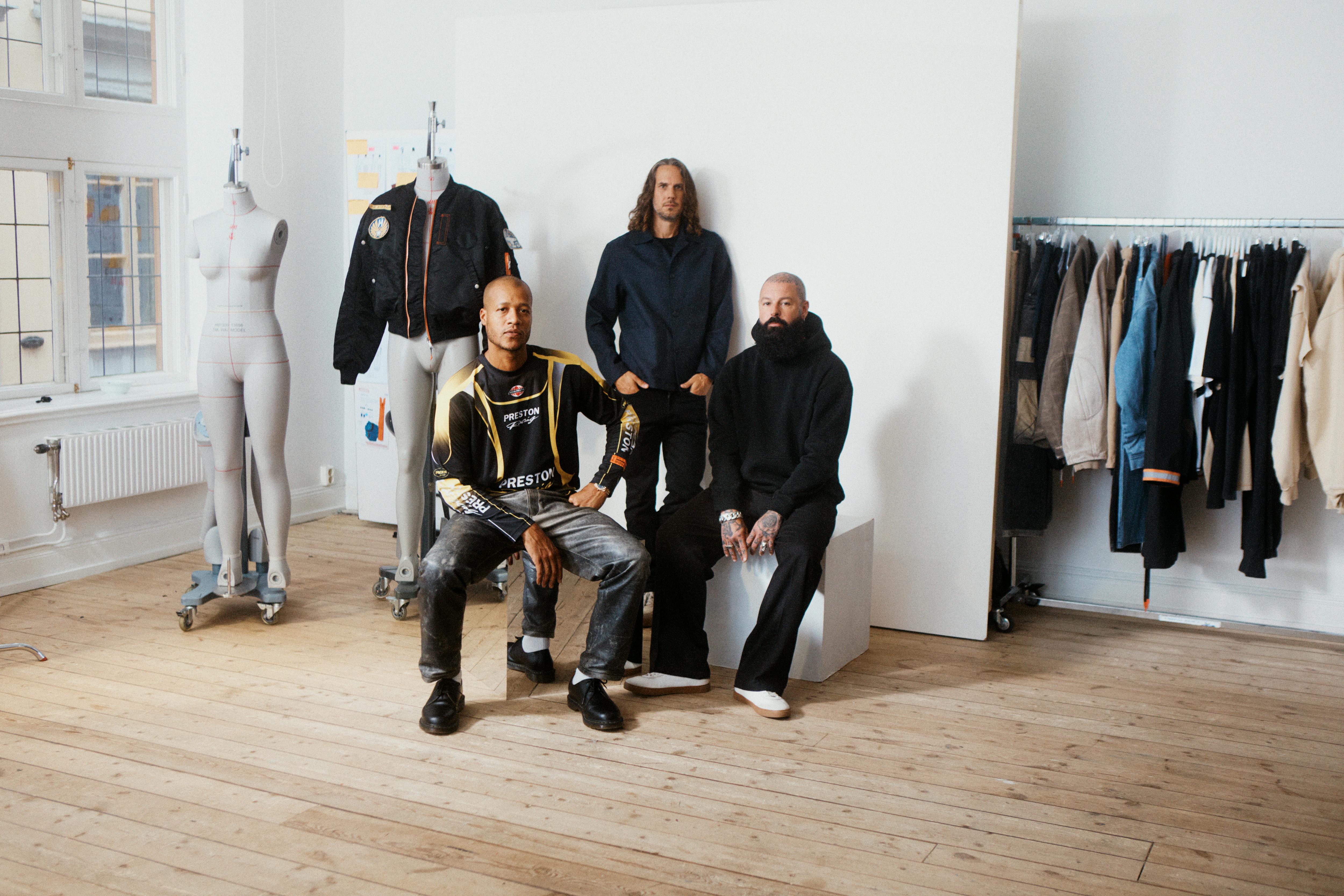 Heron Preston & H&M's menswear directors reveal the H2 collaboration, sitting in a room with mannequins and clothes on racks