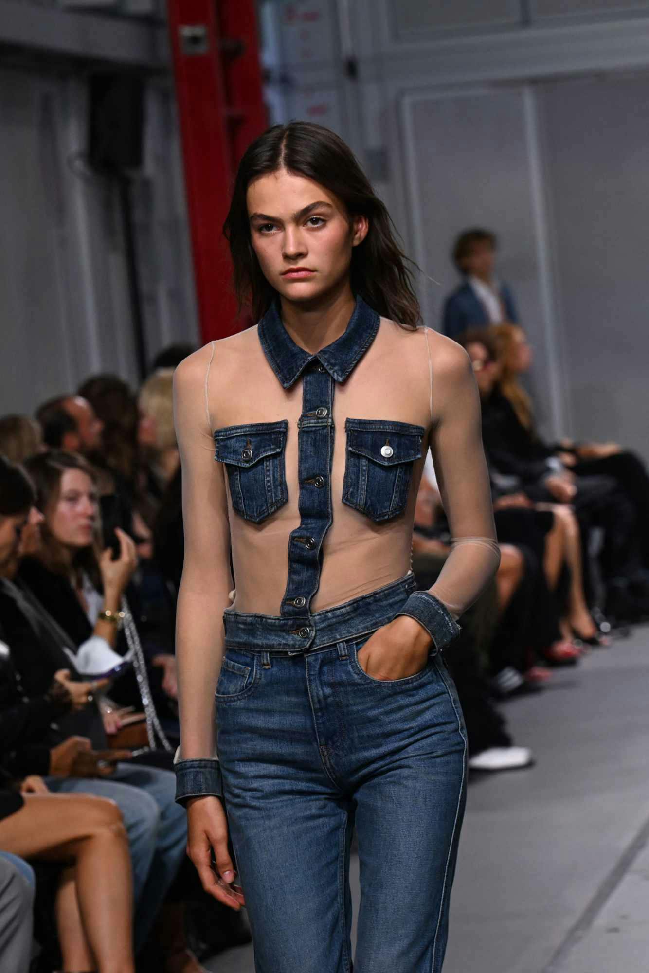 A model wears a see-through shirt with denim patches from Coperni's Spring/Summer 2024 collection runway