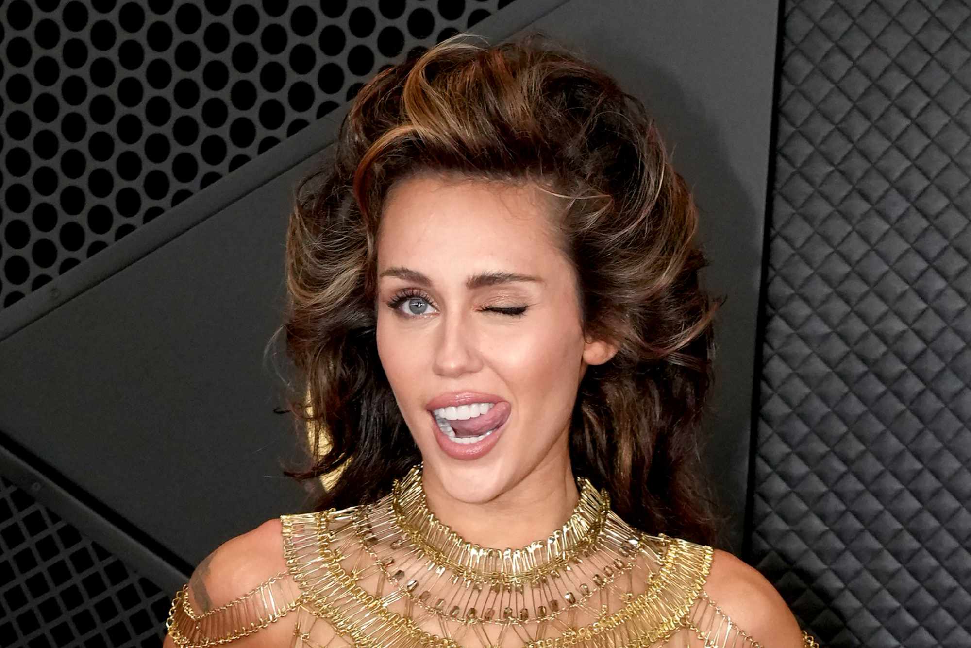 Miley Cyrus wears a gold dress & tall hair at the 2024 Grammy awards