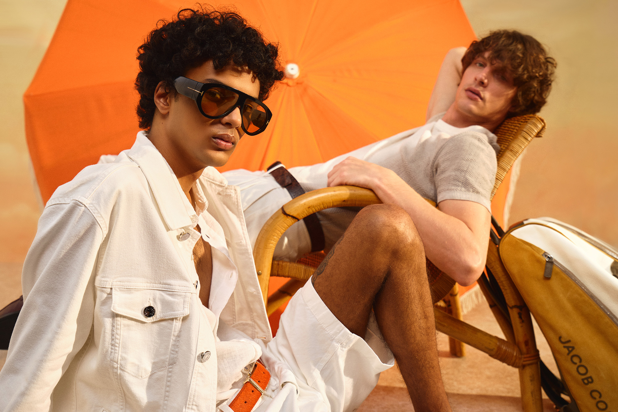 Models recline in summery looks against an orange background