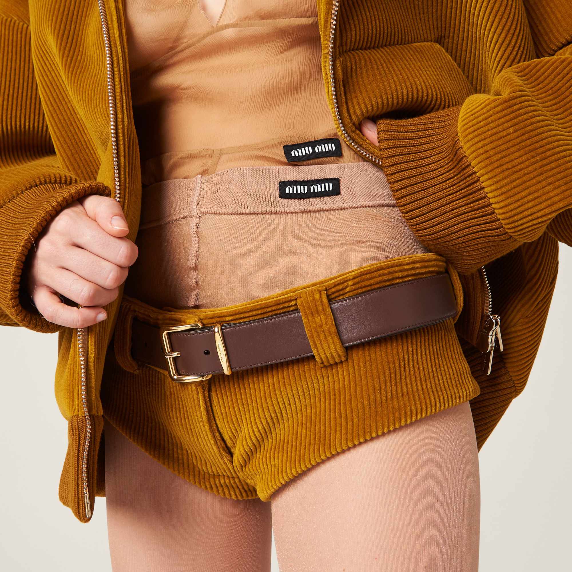 A model wears Miu Miu's brown corduroy shorts with exposed underwear