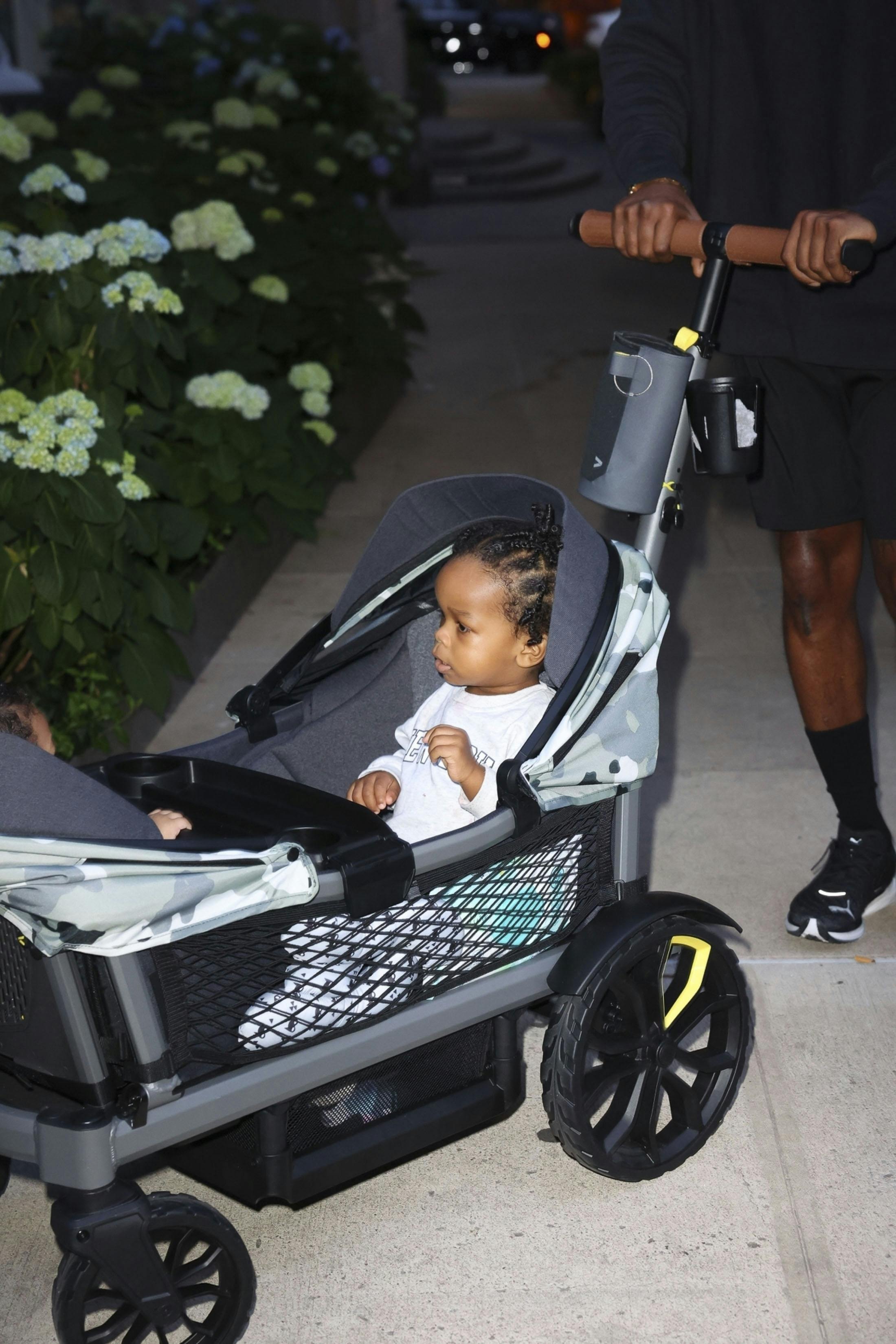 A$AP Rocky wears a black sweater, black shorts, Puma sneakers and pearl-studded Beats headphones while walking with kids RZA & Riot Rose