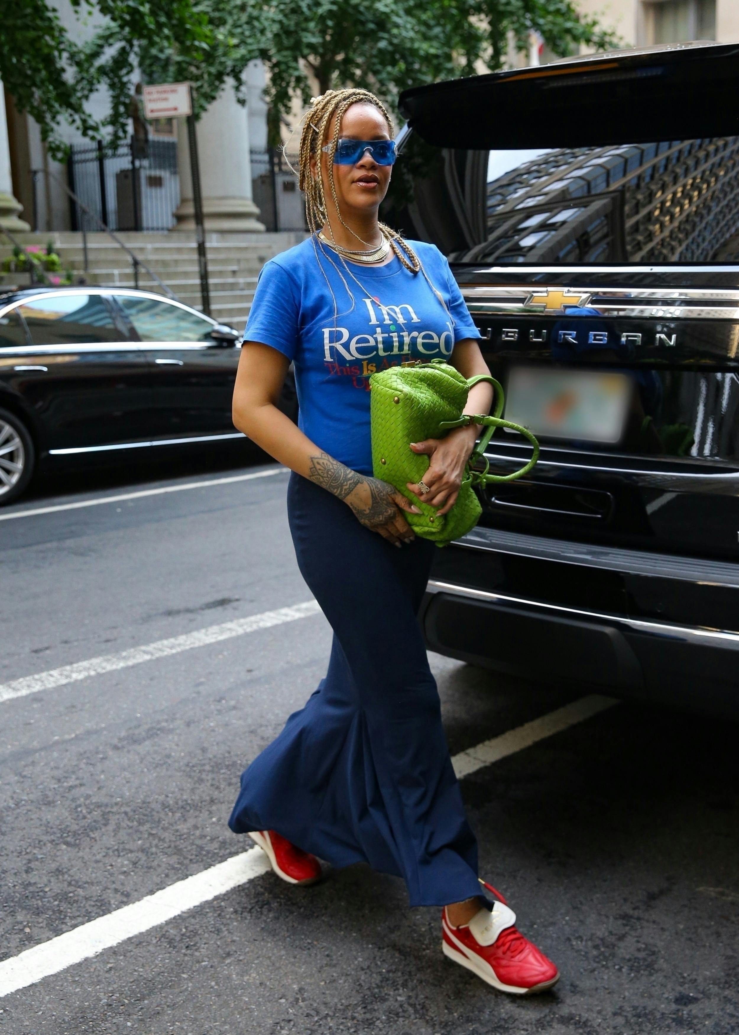 Rihanna seen in New York with a yellow Bottega Veneta handbag, blue I'm Retired T-shirt, red PUMA sneakers