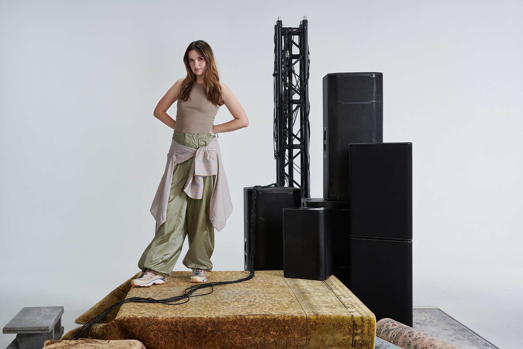 A woman strikes a powerful pose next to heavy-duty sound equipment
