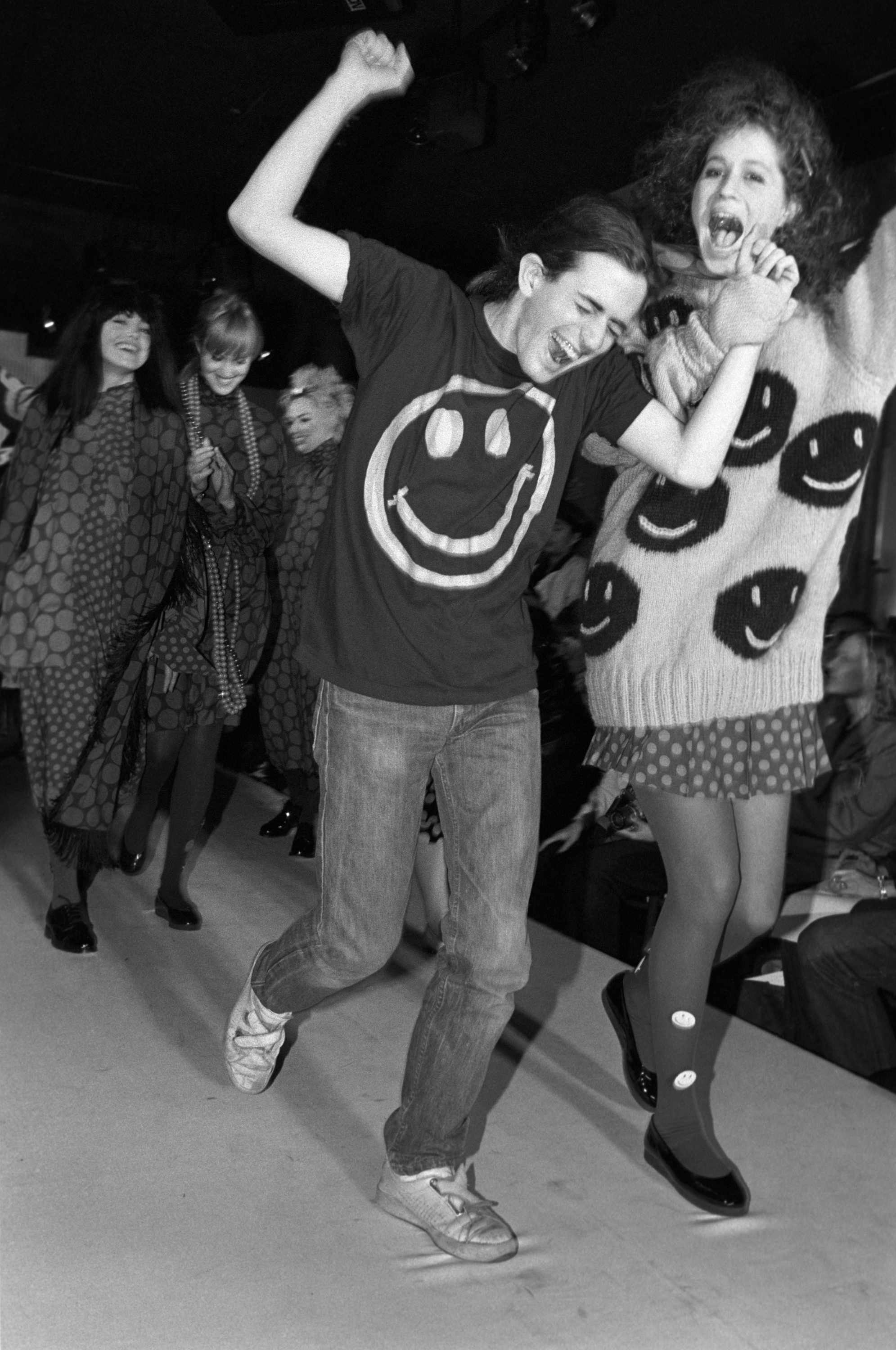Marc Jacobs wears smiley face T-shirt next to a model wearing the smiley sweater in 1985