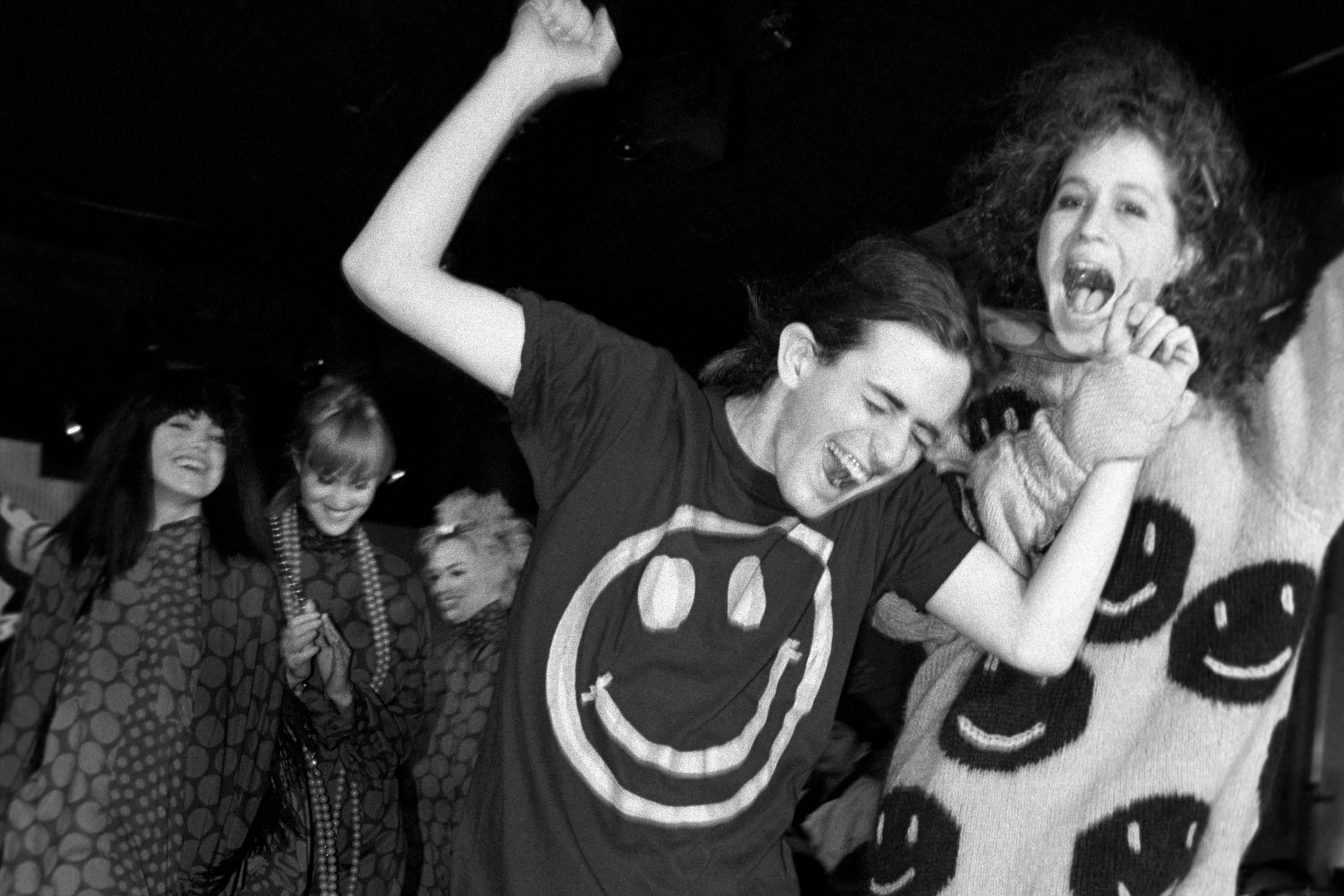 Marc Jacobs wears smiley face T-shirt next to a model wearing the smiley sweater in 1985