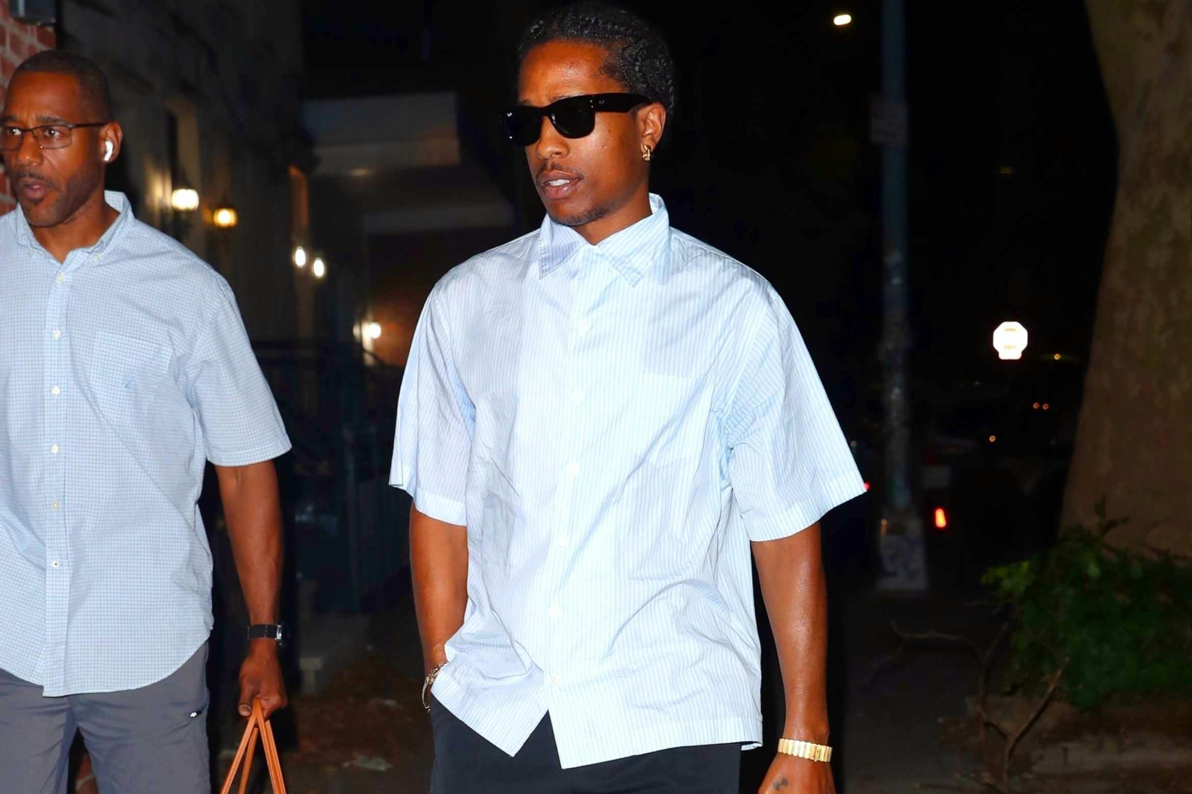 A$AP Rocky wears a short-sleeved white shirt, black pants, and black leather shoes while at a recording studio with Rihanna in July 2024