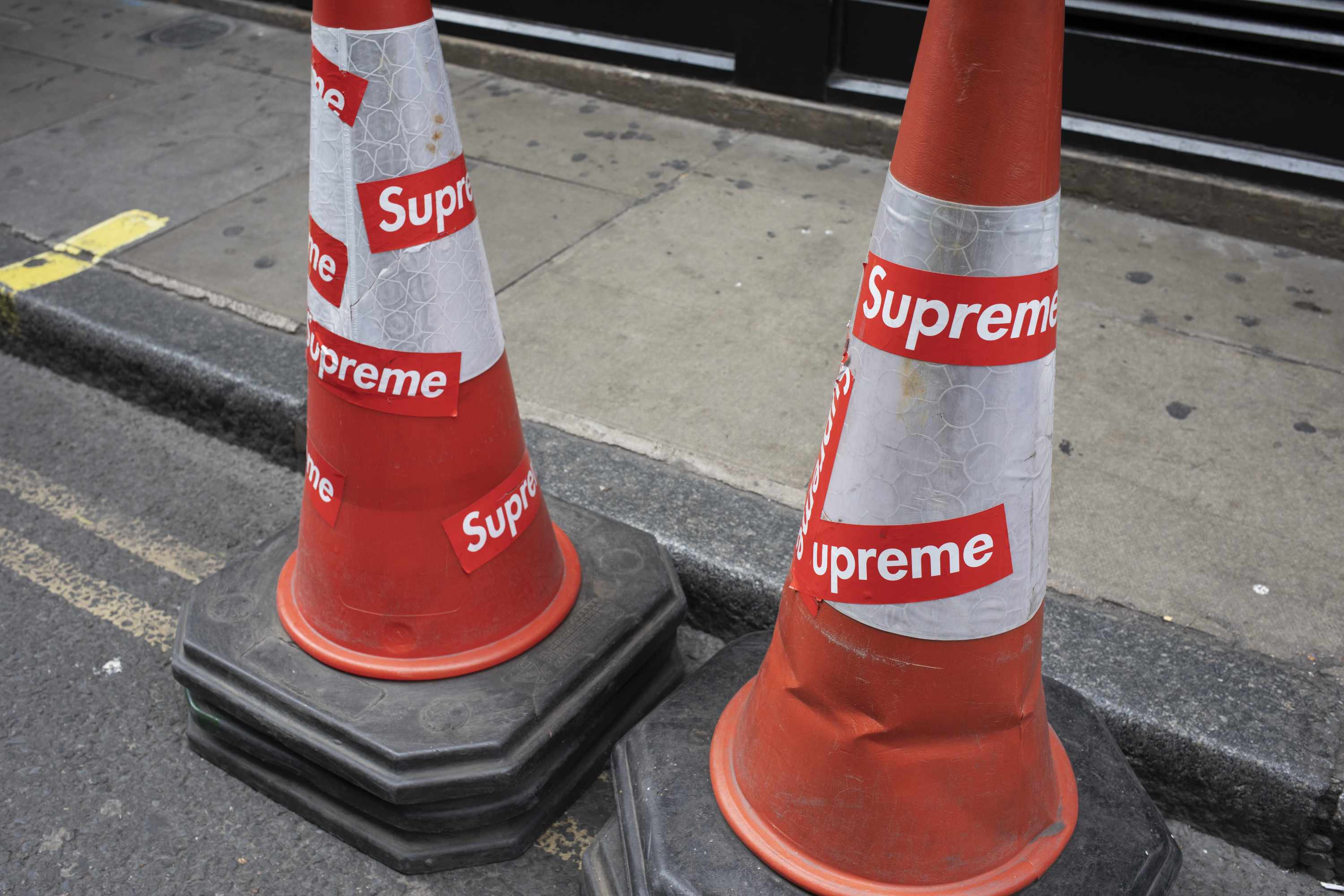 Red Supreme logo stickers on an orange traffic cone