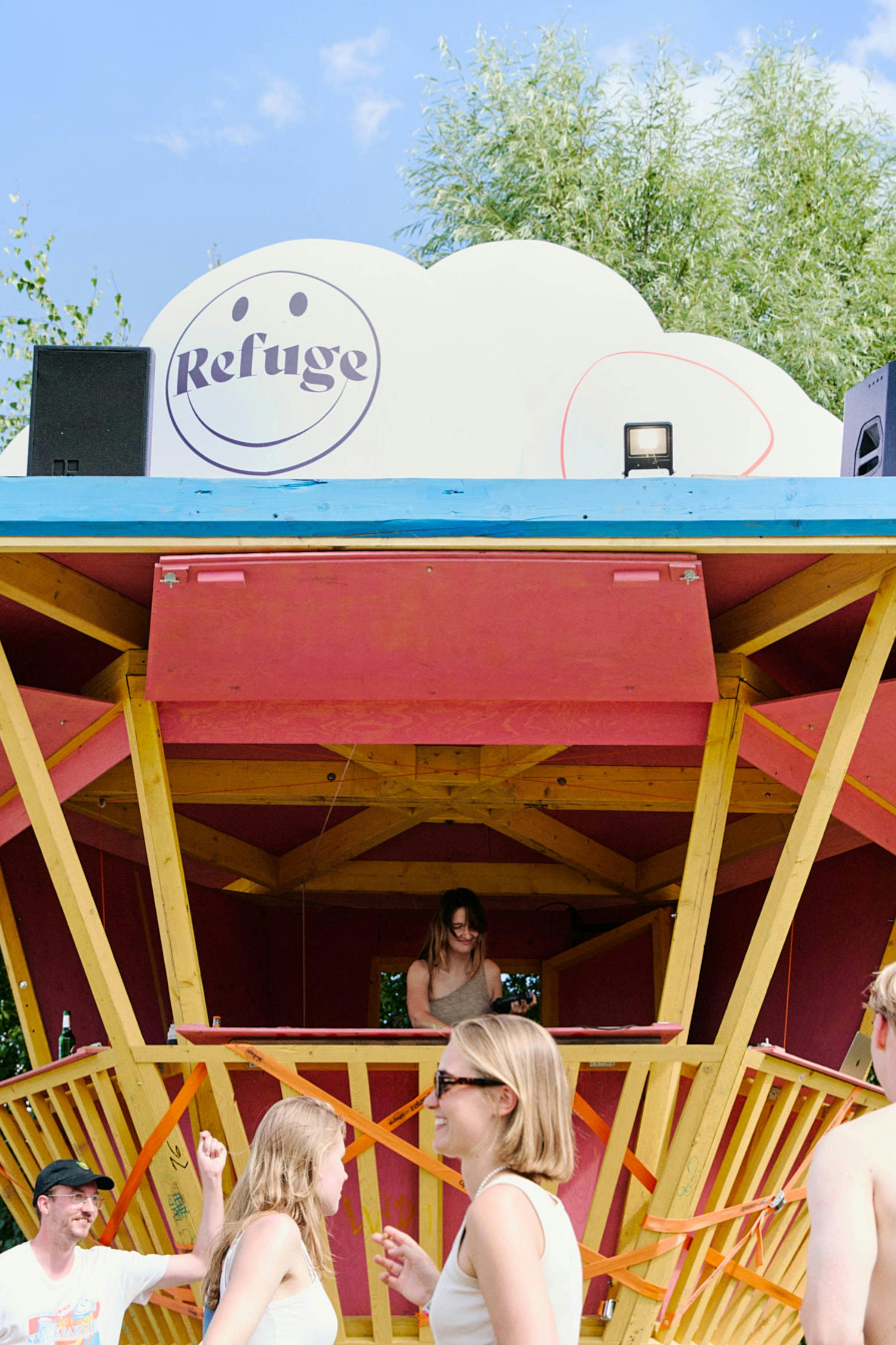 DJ playing in a colourful booth at a festival