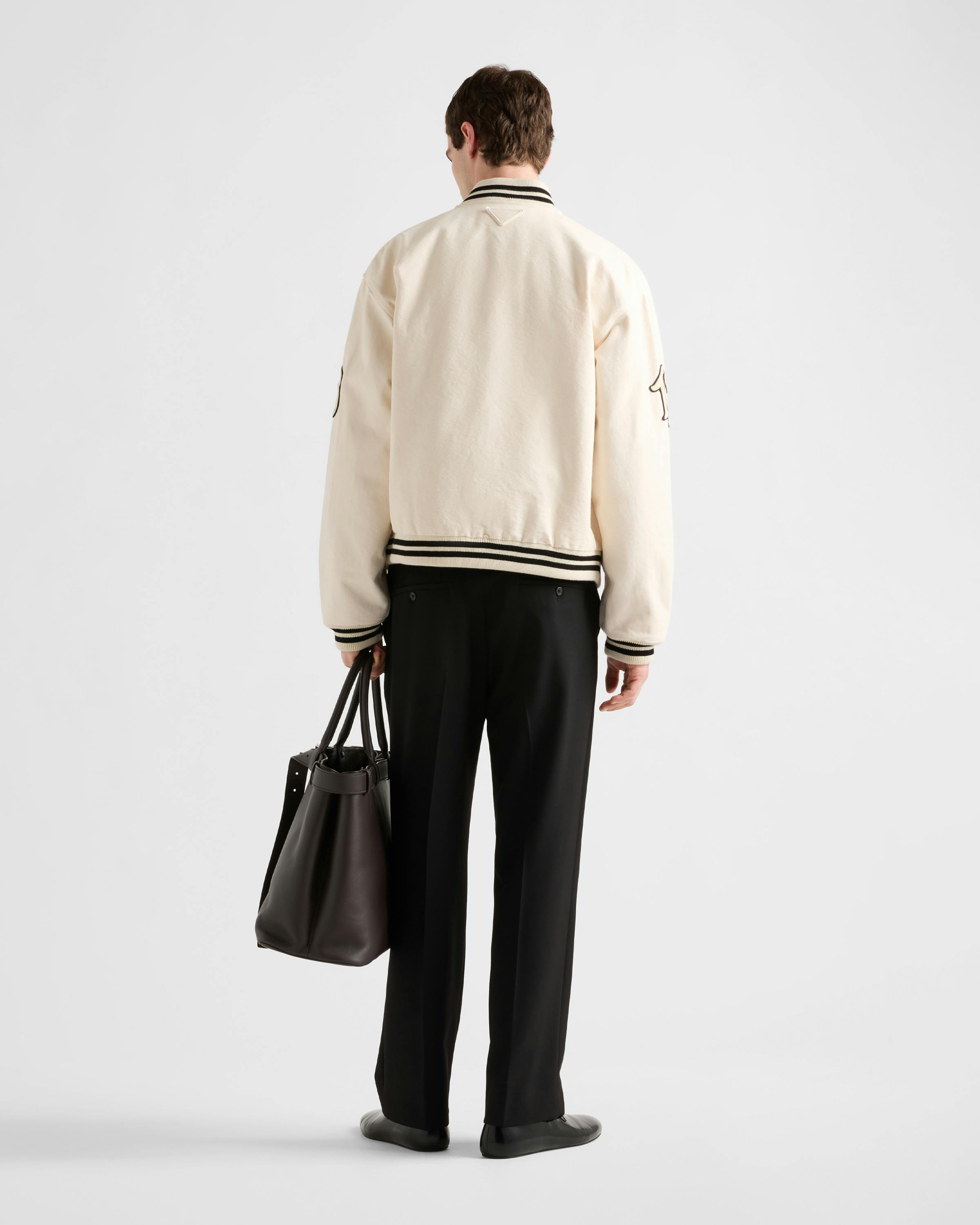 Prada's 1913 menswear capsule, including white varsity jacket, black bomber and knit cardigan