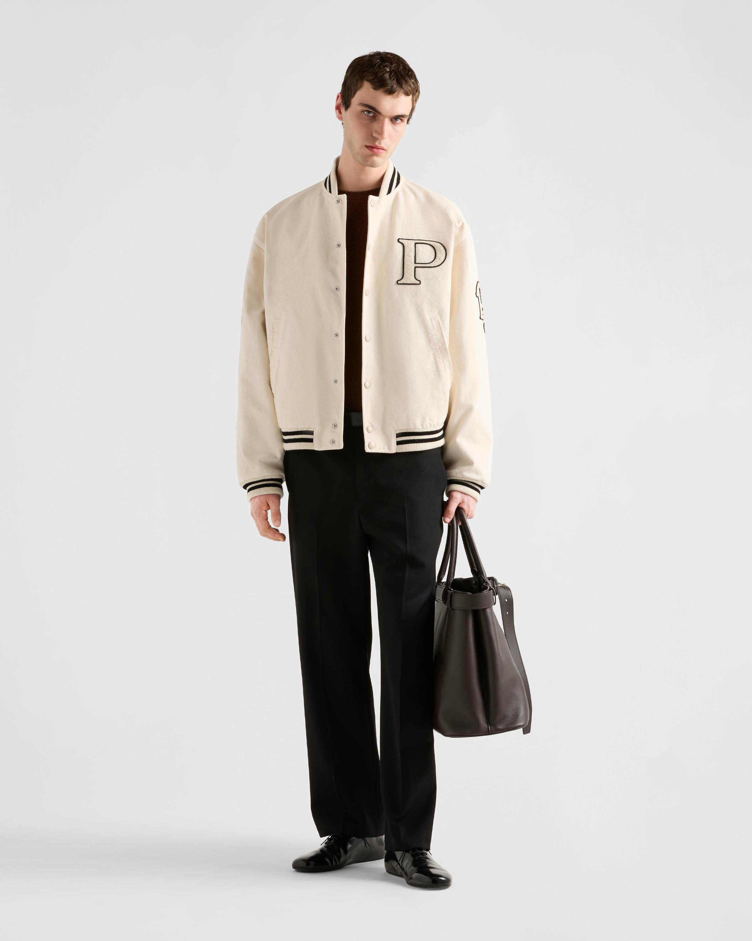 Prada's 1913 menswear capsule, including white varsity jacket, black bomber and knit cardigan