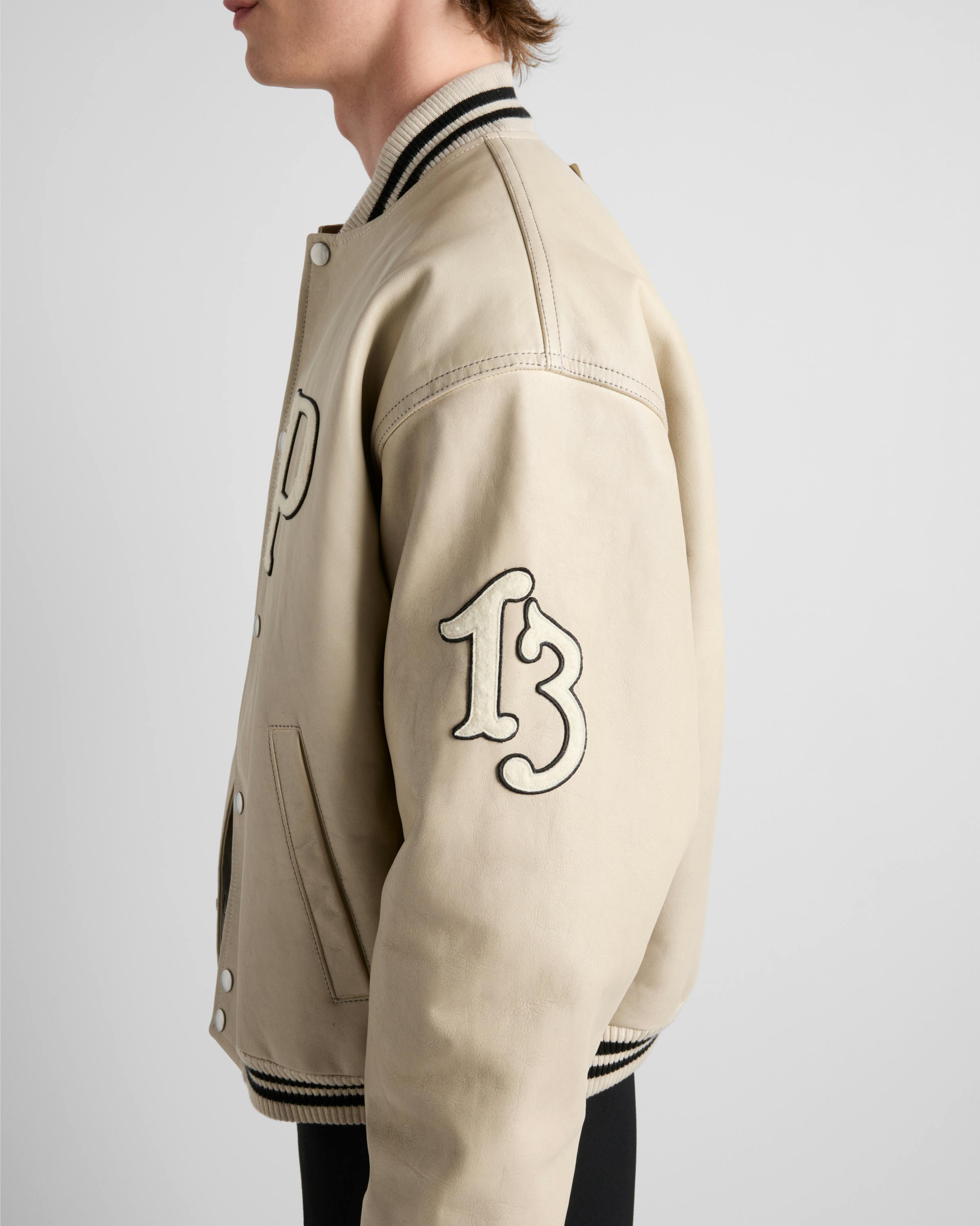 Prada's 1913 menswear capsule, including white varsity jacket, black bomber and knit cardigan