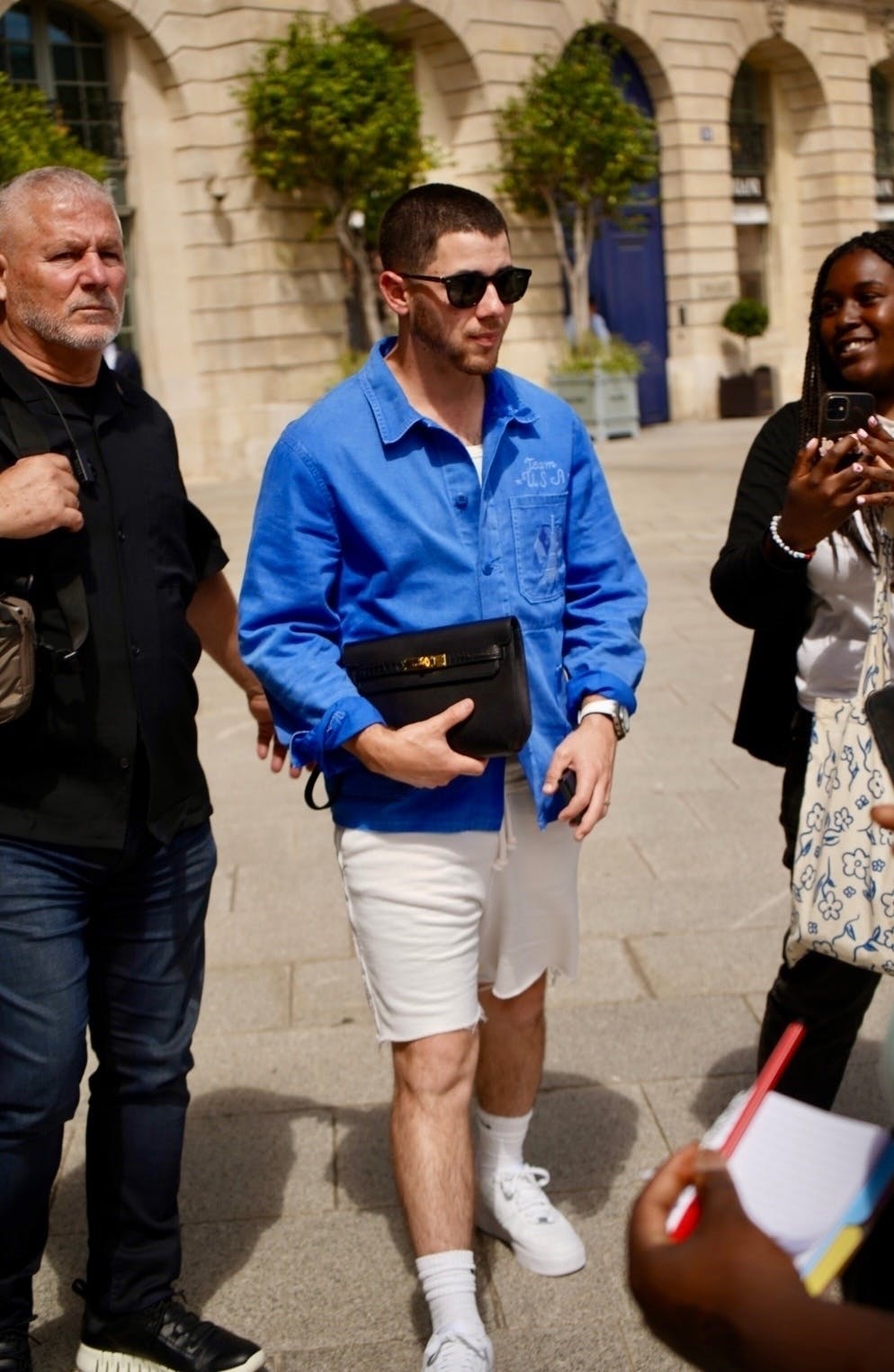 Nick Jonas carrying an Hermès Kelly Depeches 25 Clutch in Paris during the 2024 Olympics