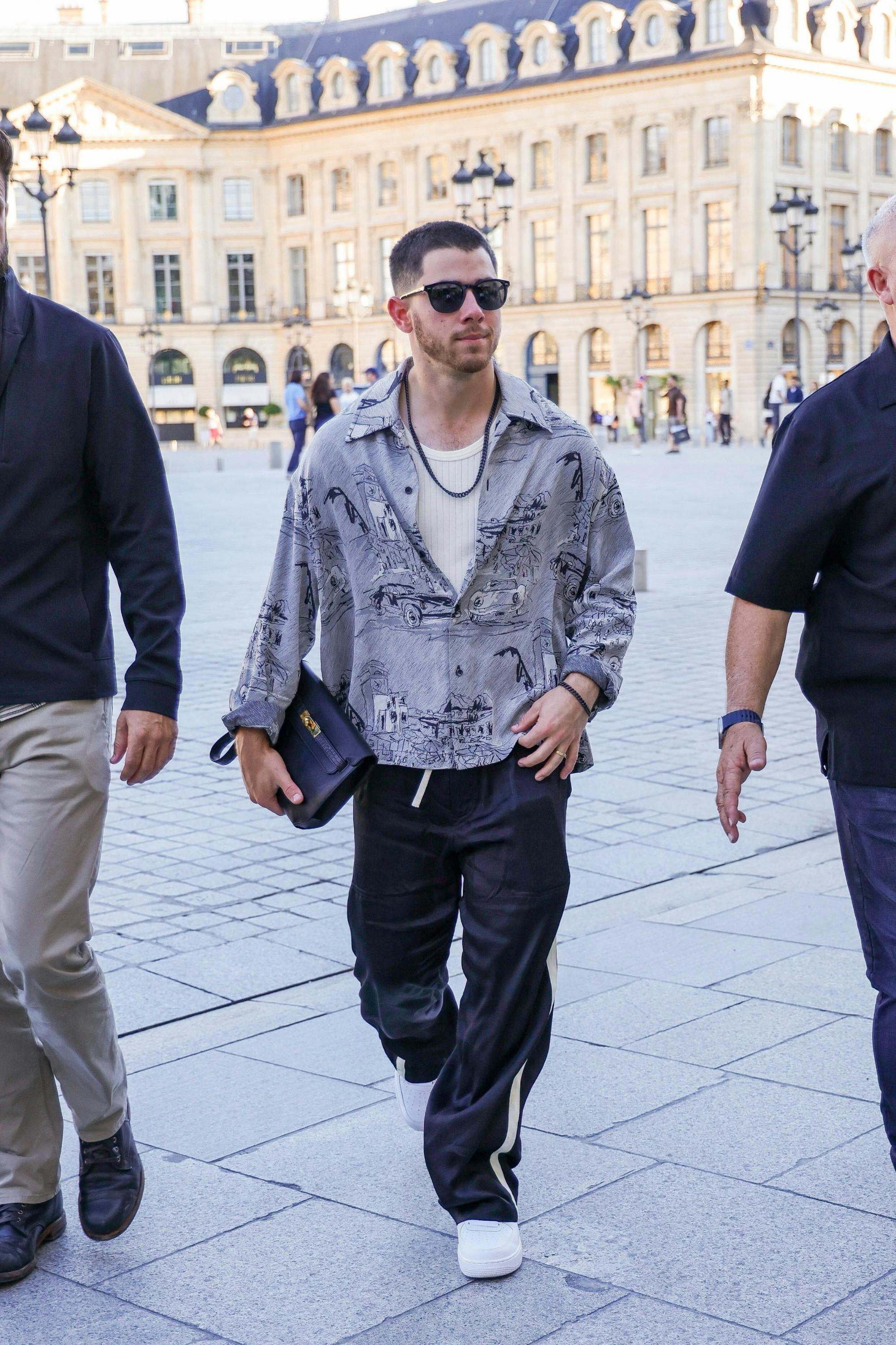 Nick Jonas carrying an Hermès Kelly Depeches 25 Clutch in Paris during the 2024 Olympics