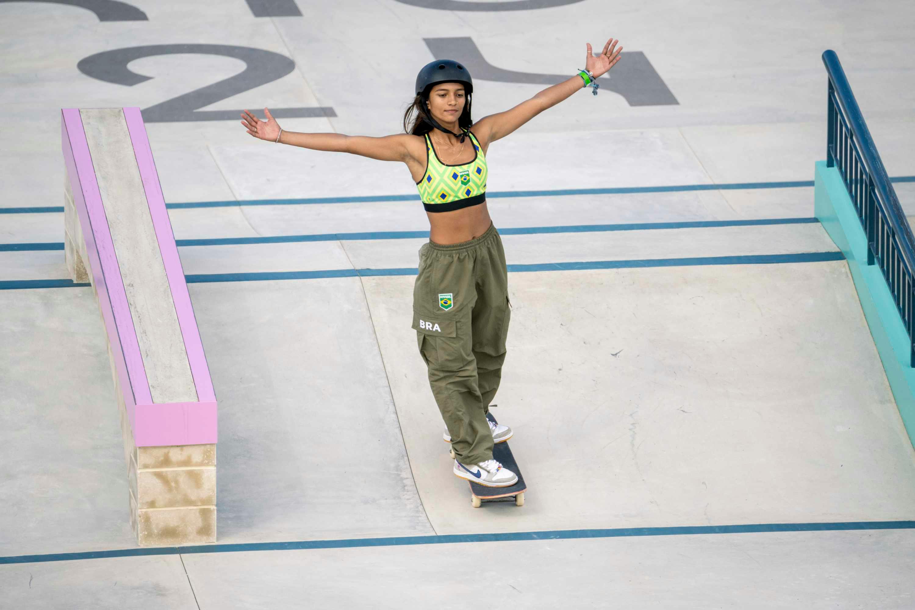 Rayssa Leal wears a yellow top and green cargo pants as her Brazilian uniform at the 2024 Olympics street skating games