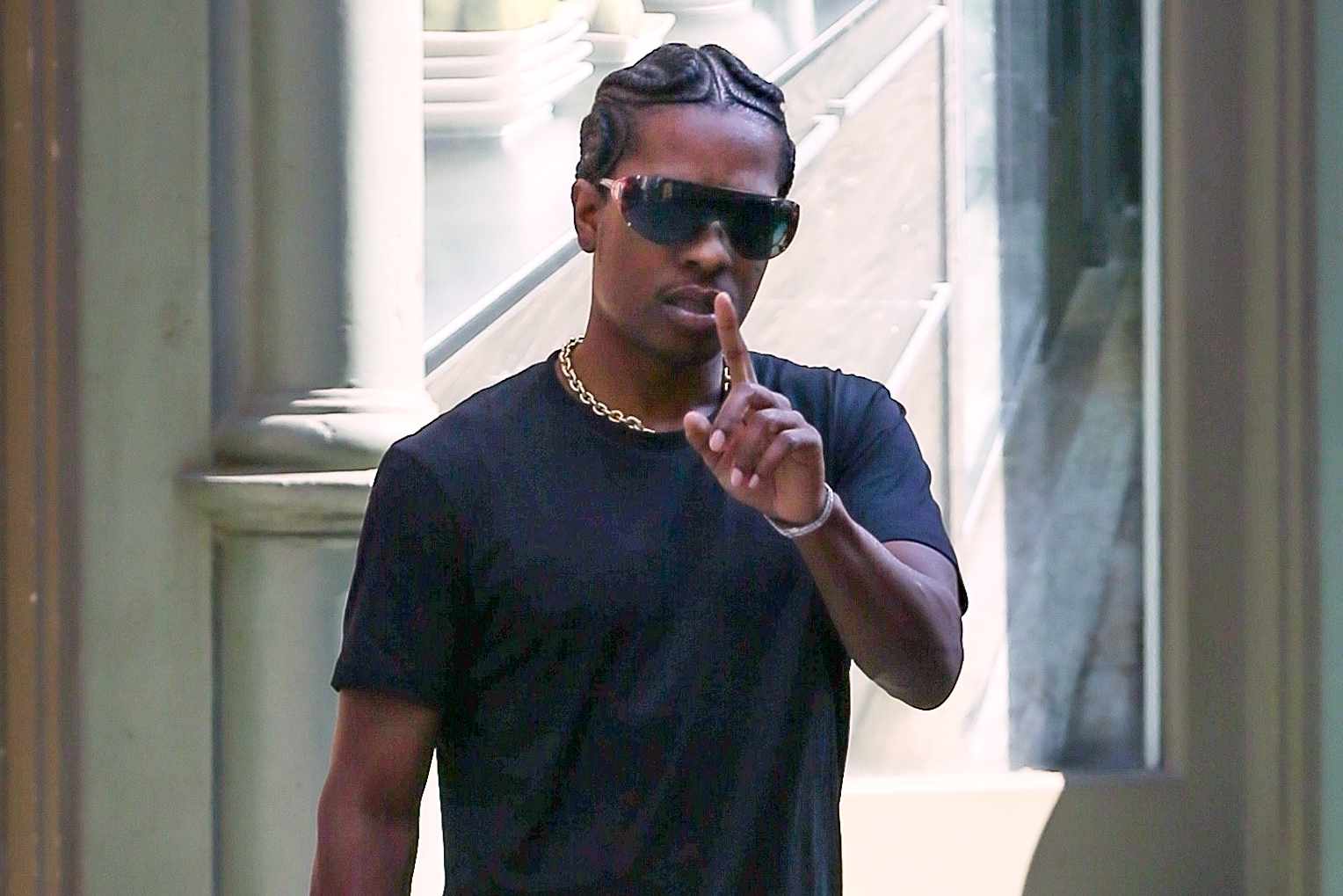A$AP Rocky wears shield sunglasses, a black T-shirt, blue jeans and black leather shoes in New York on July 31