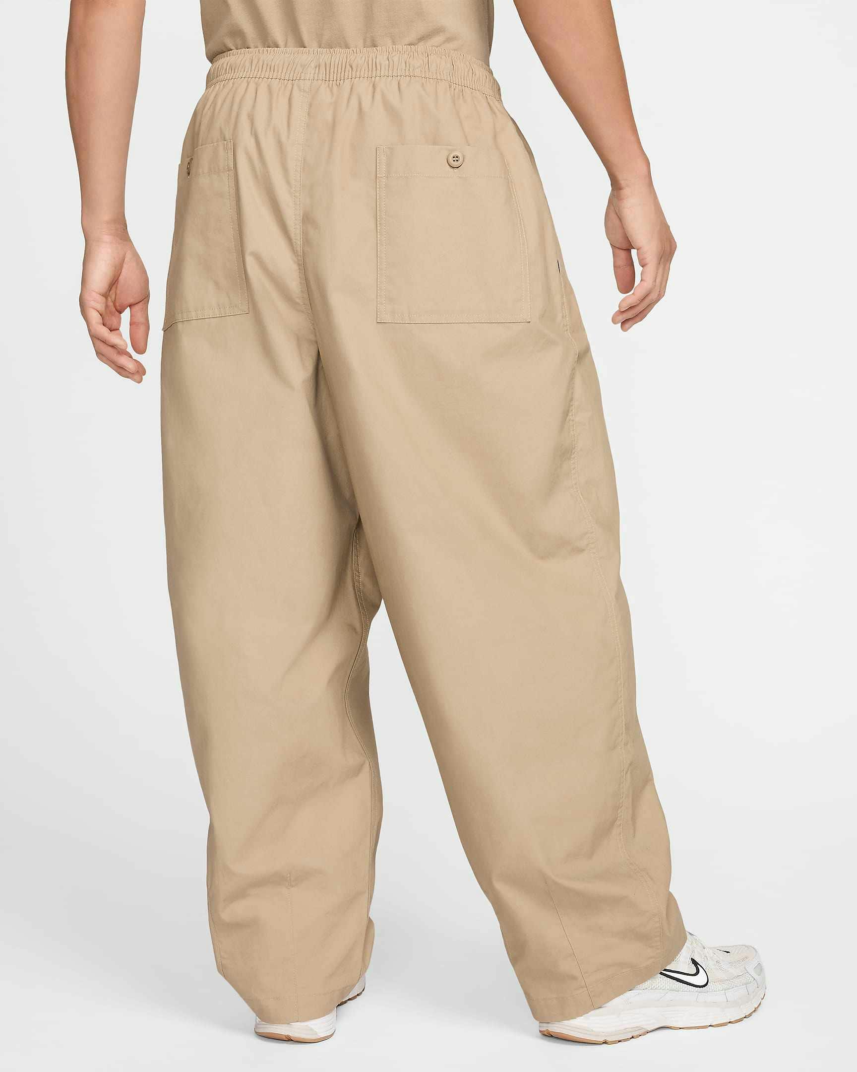 Nike Balloon Pant in beige and black colorways, with an elastic waist, pleats and loose leg