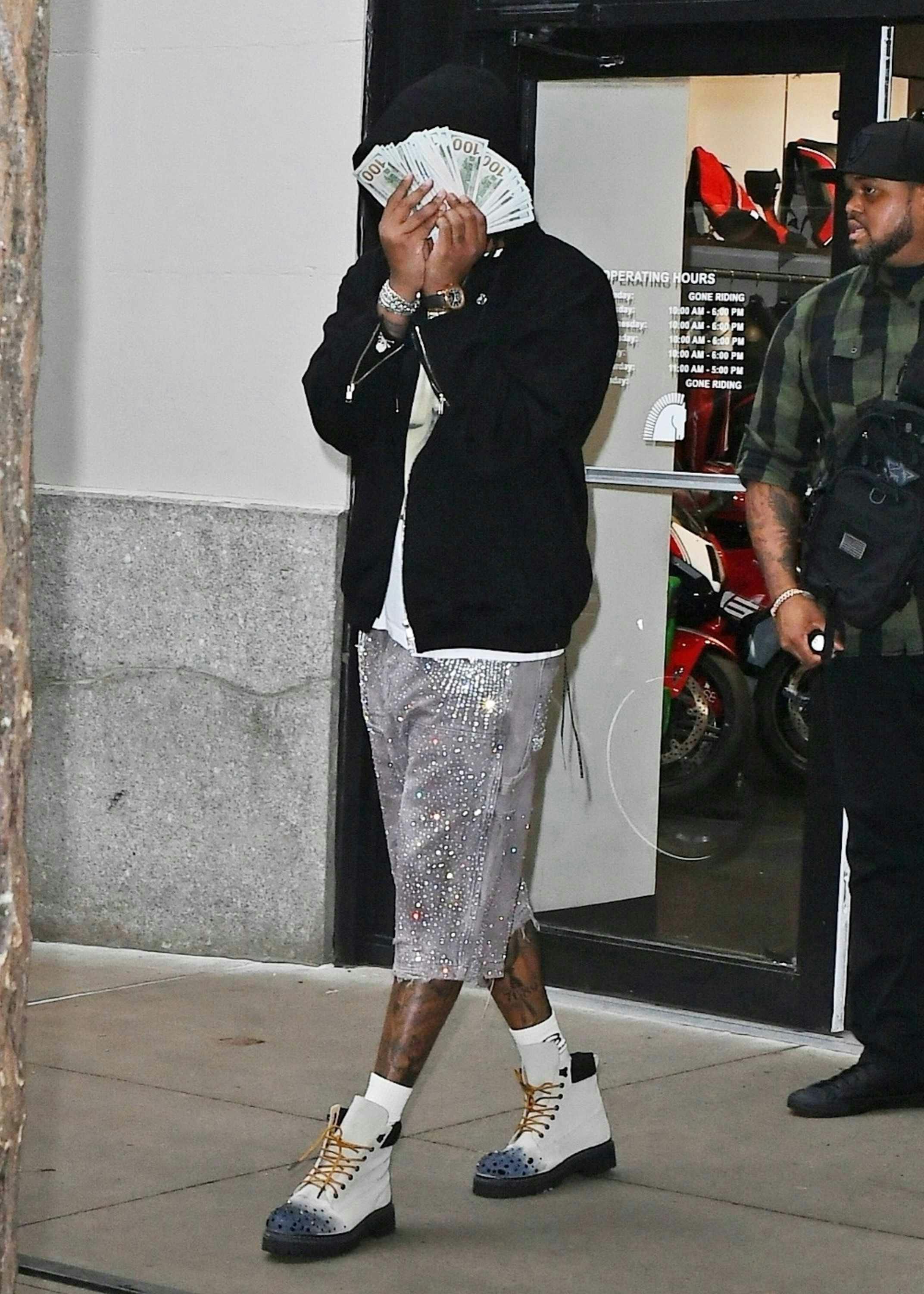 Future wears a black hoodie, sunglasses, white T-shirt, studded denim shorts and white boots at Ducati's NYC store