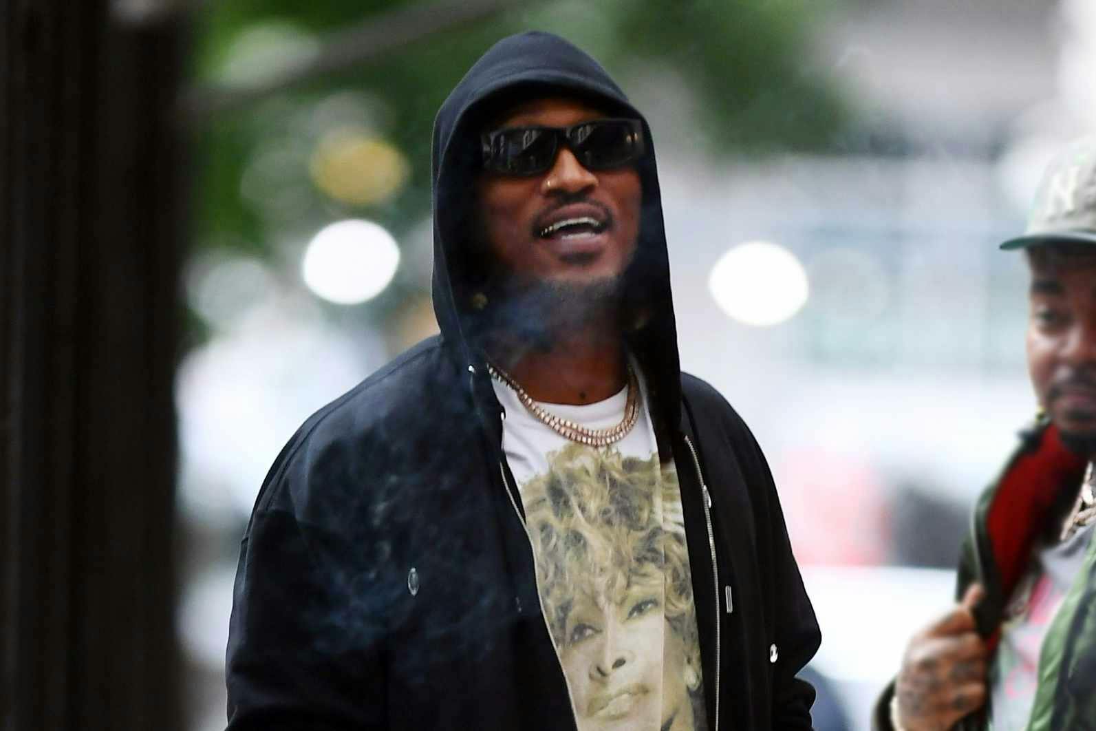 Future wears a black hoodie, sunglasses, white T-shirt, studded denim shorts and white boots at Ducati's NYC store