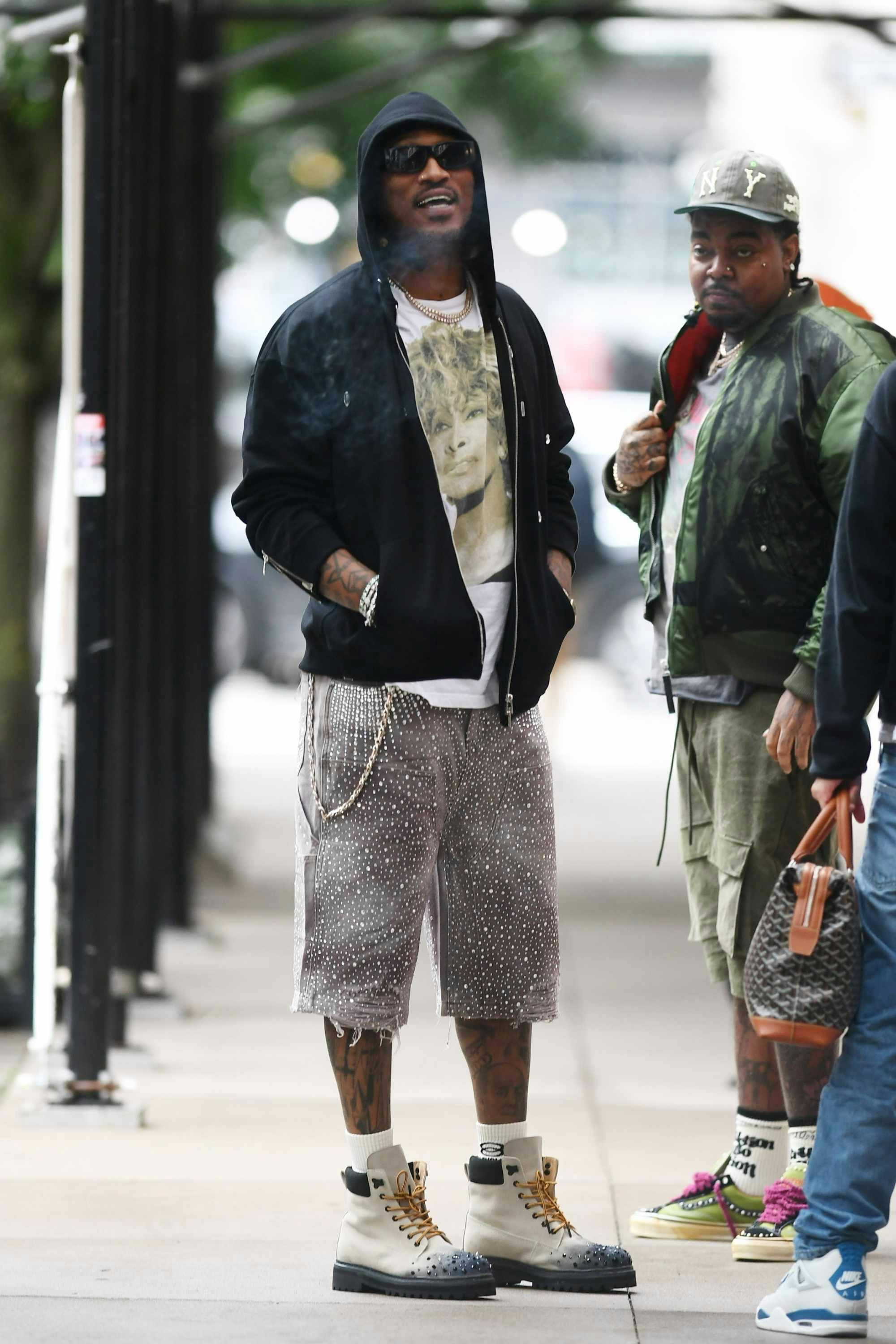 Future wears a black hoodie, sunglasses, white T-shirt, studded denim shorts and white boots at Ducati's NYC store