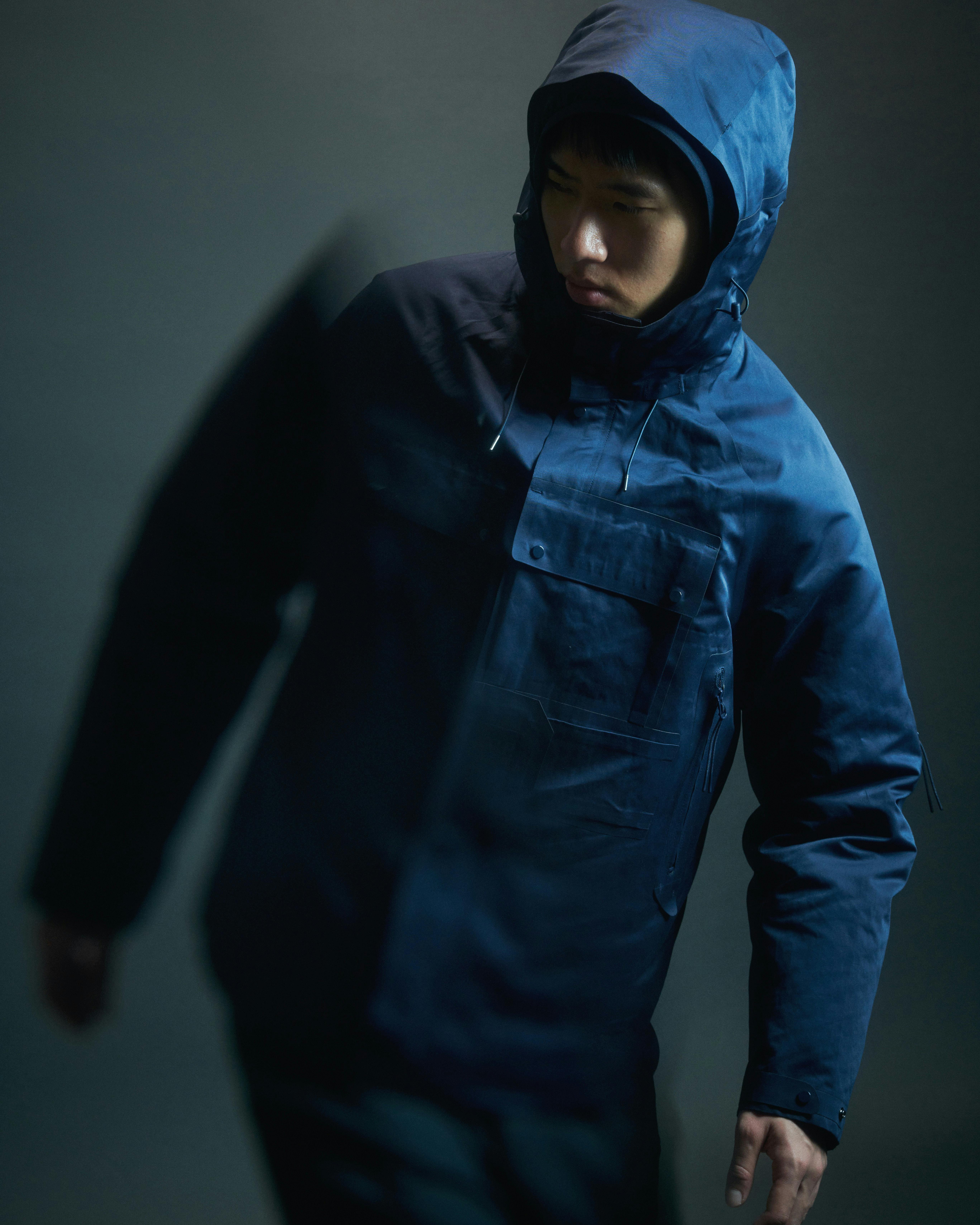 Blurred motion image of a model wearing a blue hooded utility jacket