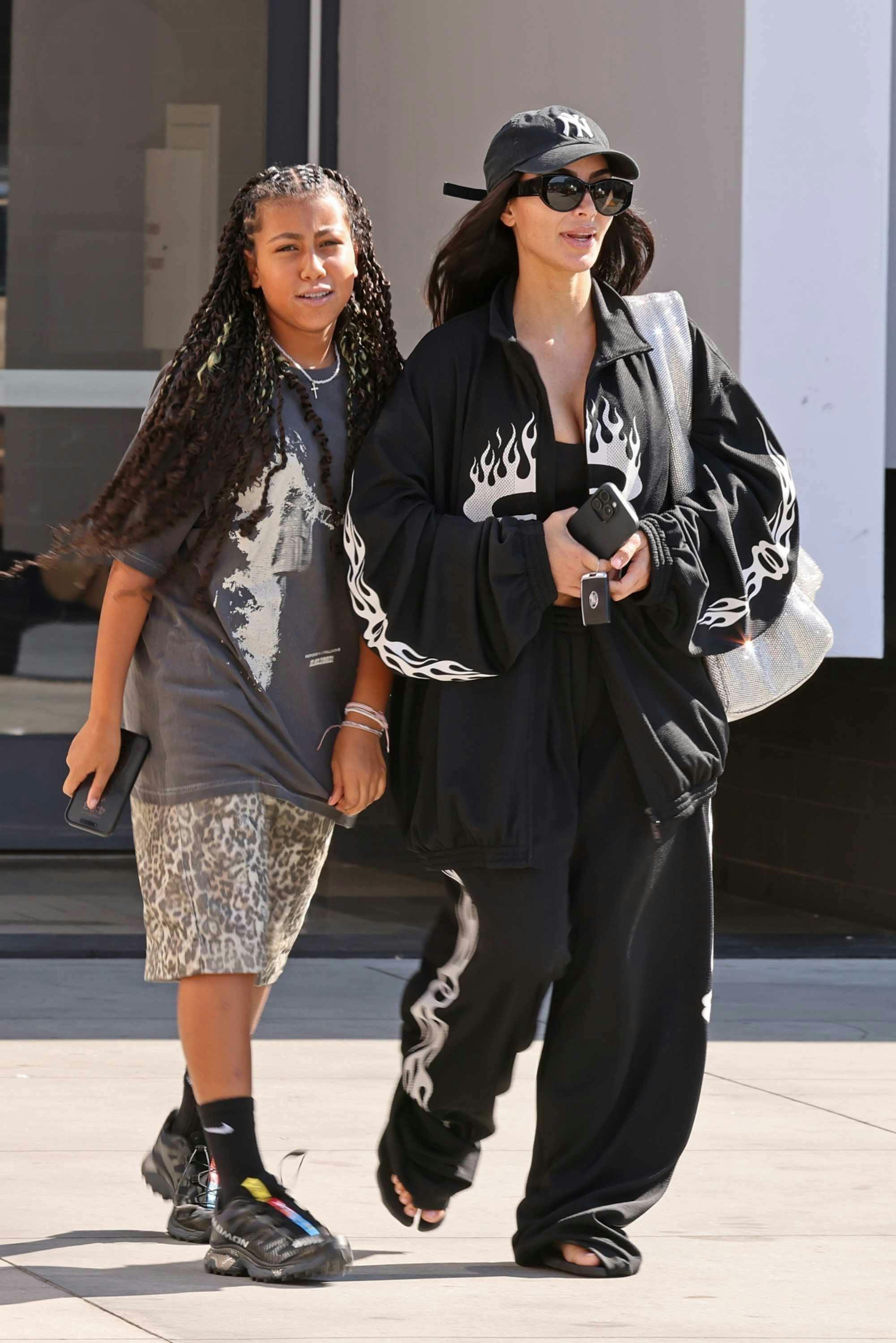 Kim kardashian wears a black sweatsuit with flames and flip flops out with daughter north west in los angeles