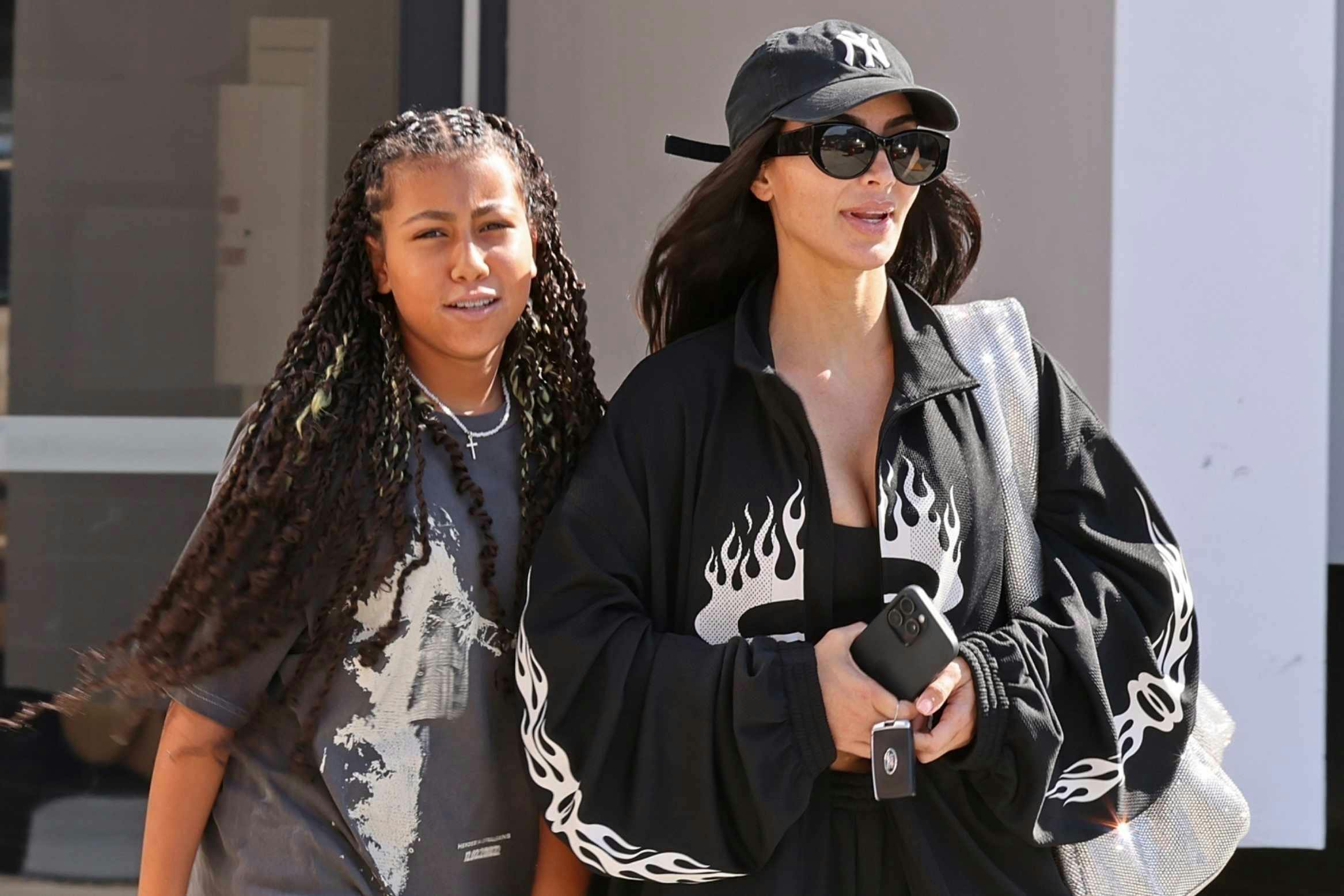 Kim kardashian wears a black sweatsuit with flames and flip flops out with daughter north west in los angeles