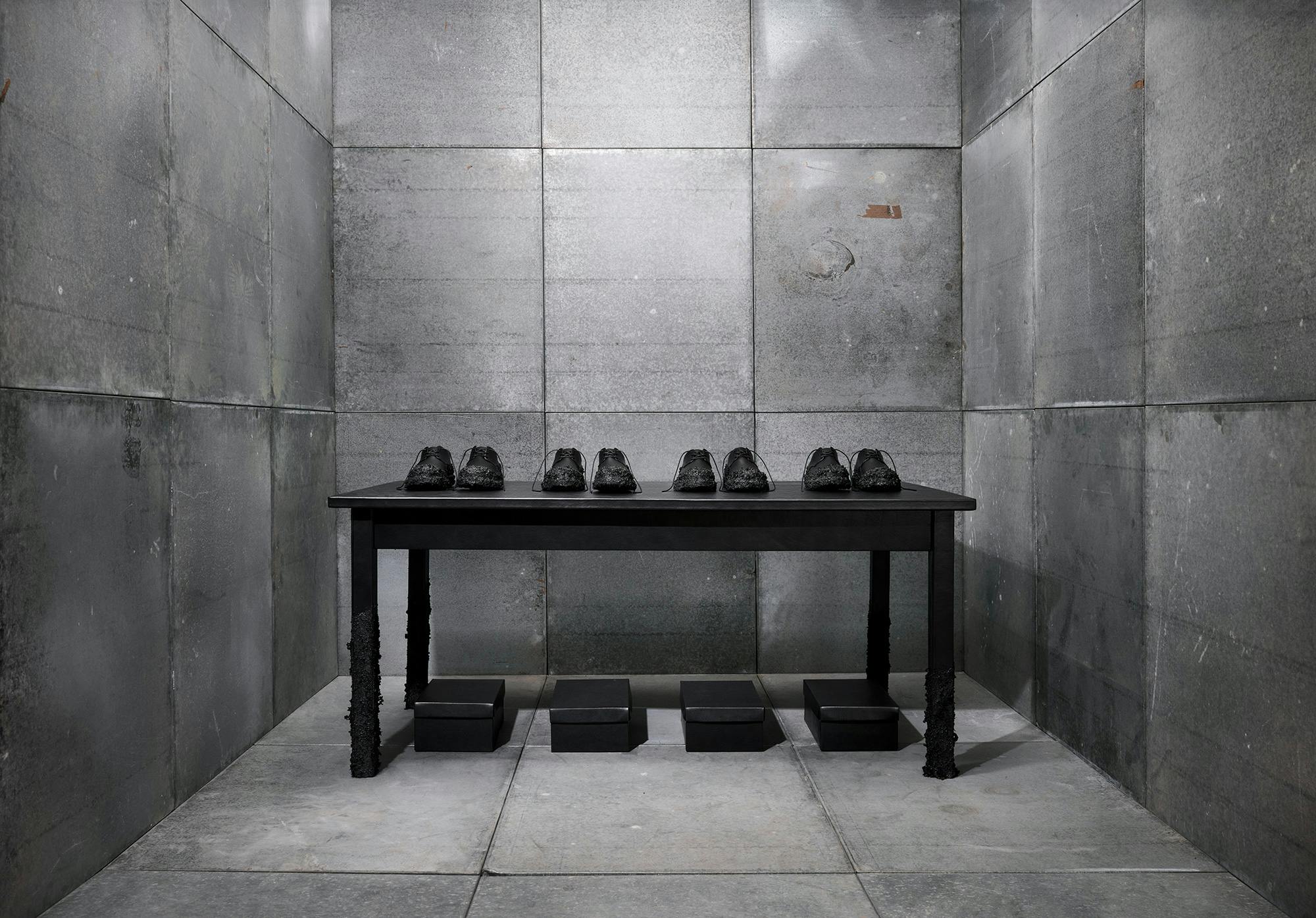 Artistic arrangement of a line of black shoes on top of a black table