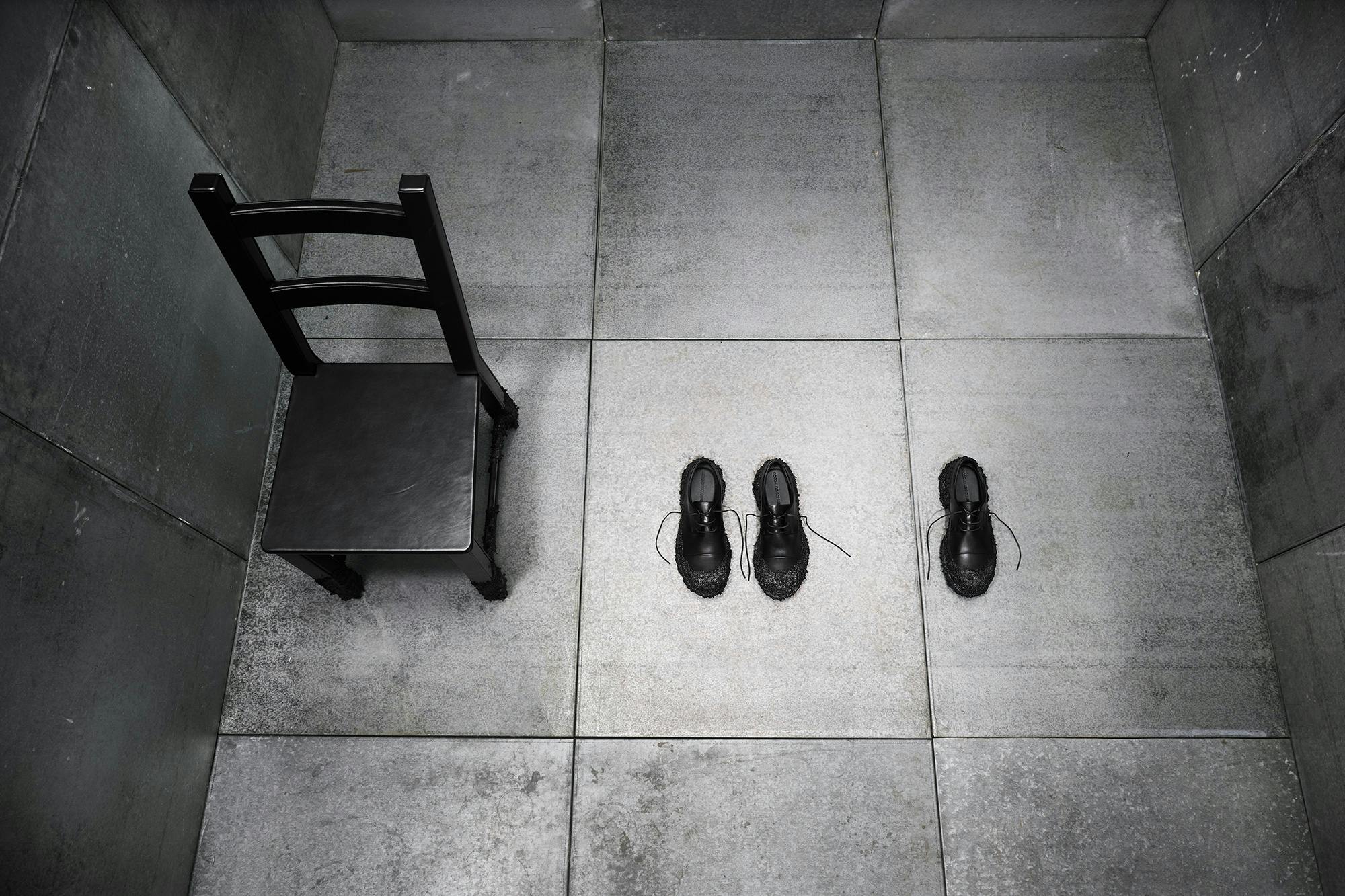 Artistic arrangement of a leather chair and leather shoes in a black room