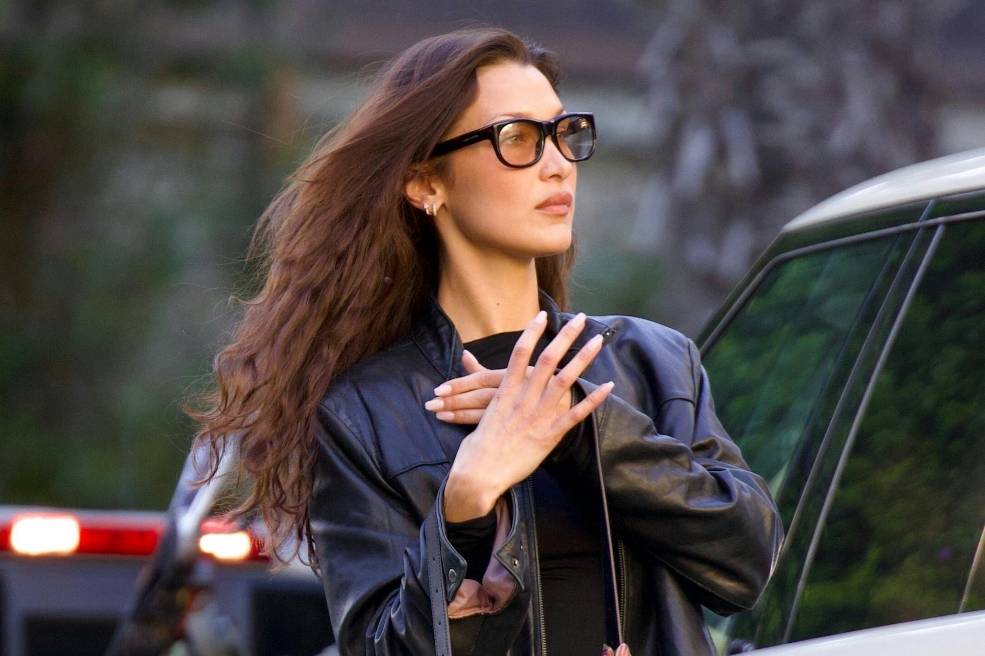 Bella Hadid wears glasses, leather jacket, and Coach bag in Los Angeles