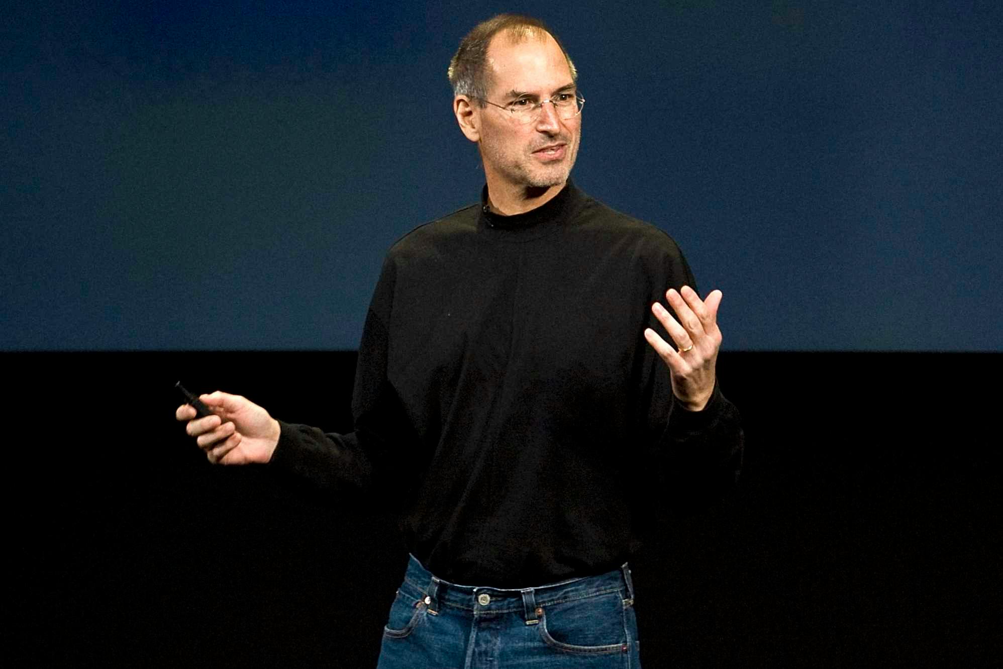 steve jobs at an apple presentation wearing a black turtleneck and blue levis jeans