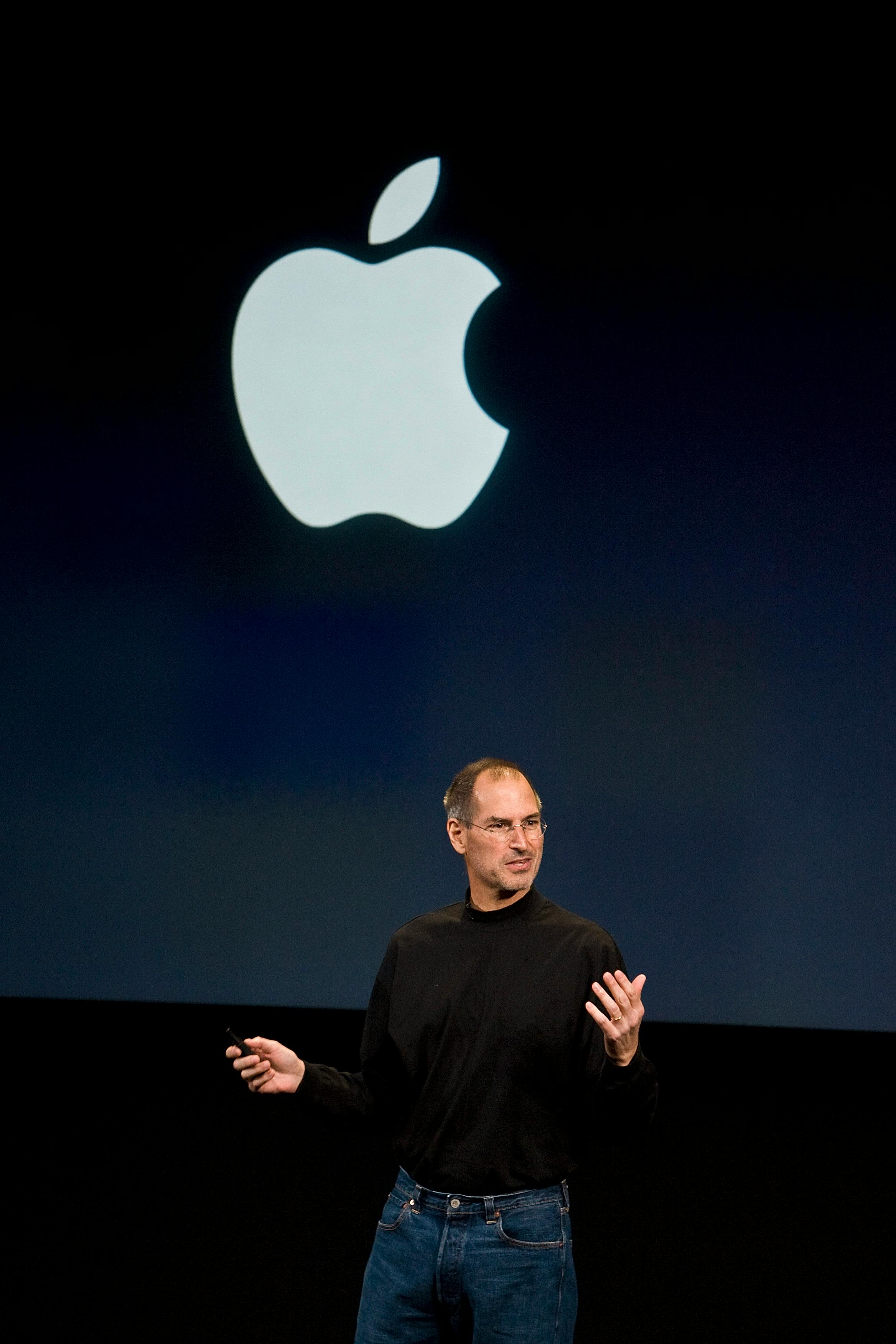 steve jobs at an apple presentation wearing a black turtleneck and blue levis jeans